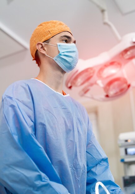 Trabajador de medicina con uniforme y máscara. Apuesto médico cirujano especialista.