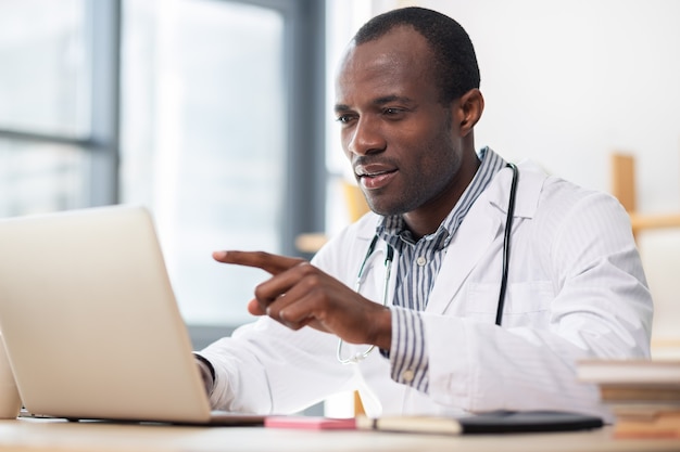 Trabajador médico concentrado leyendo artículo científico mientras tiene descanso