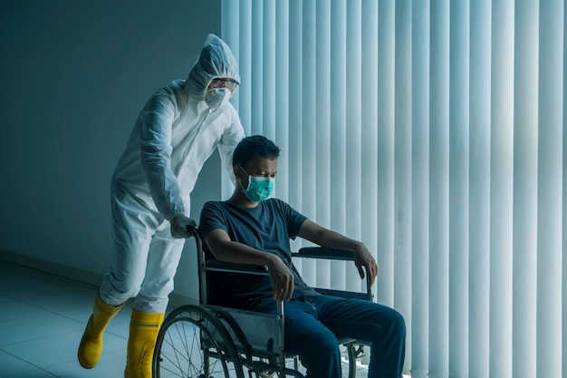Trabajador médico empujando al paciente en silla de ruedas