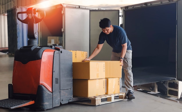 Foto trabajador mensajero levantamiento de cajas de paquetes apilamiento en paletas cadena de suministro almacén logística de carga