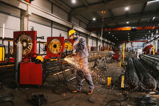 Un trabajador metalúrgico está moliendo el marco metálico en la instalación