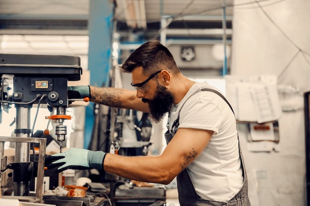 Un trabajador metalúrgico perforando un agujero en una pieza metálica en el taller