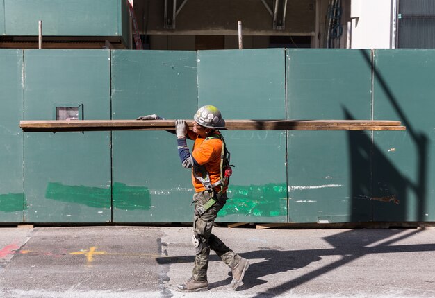 Foto el trabajador en mono lleva tablas en el sitio de construcción