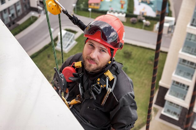 Trabajador de montañismo industrial se cuelga sobre edificio residencial durante la instalación