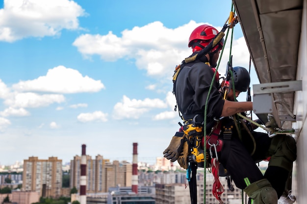 Trabajador de montañismo industrial se cuelga sobre edificio residencial durante la instalación