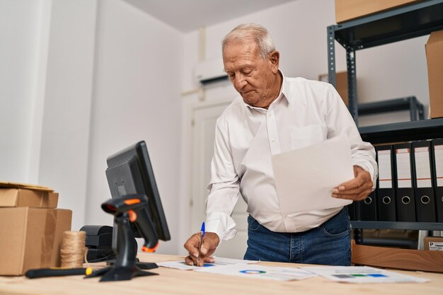 Trabajador de negocios de comercio electrónico de hombre mayor escribiendo en el documento en la oficina