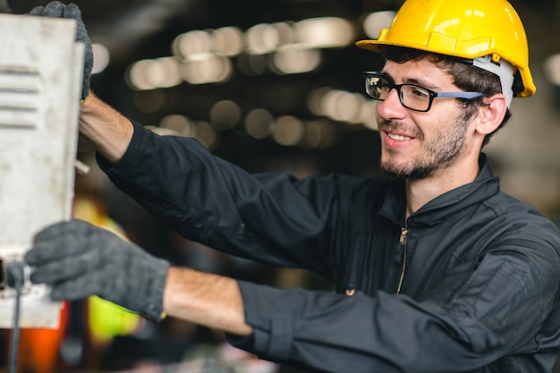 Trabajador de nueva generación estadounidense joven profesional de alta habilidad feliz disfruta sonriendo para trabajar en una fábrica industrial pesada operador de control de máquina