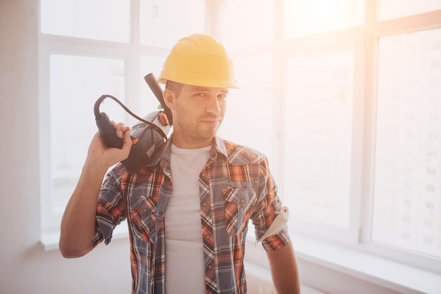 El trabajador o constructor tiene una taza de café en sus manos y mira la tableta