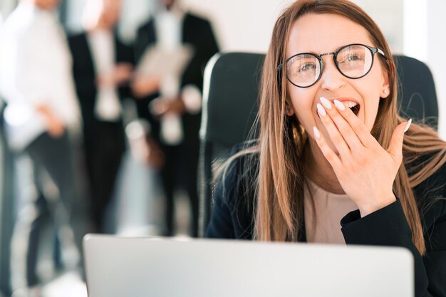 Foto trabajador de oficina de mujer riendo en la computadora portátil