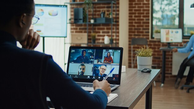 Trabajador de oficina que asiste a una reunión de negocios en una videollamada en la sala de juntas, usando una teleconferencia en línea para explicar la nueva estrategia de la empresa y la visión de desarrollo. Llamada remota de teletrabajo por videoconferencia.