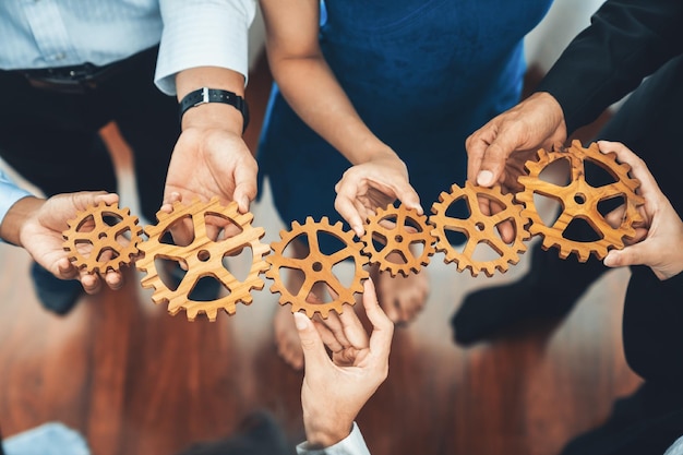 Foto trabajador de oficina sosteniendo la rueda dentada como unidad y trabajo en equipo en el concepto de lugar de trabajo corporativo diversos colegas hombres de negocios que muestran el símbolo de un sistema visionario y un mecanismo para el éxito empresarial concord