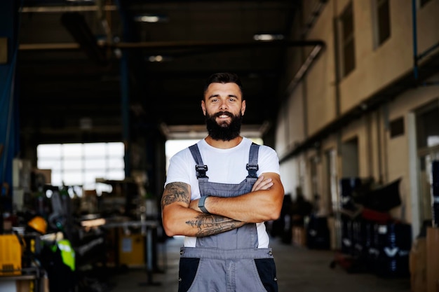 Un trabajador orgulloso de pie en el taller y sonriendo a la cámara