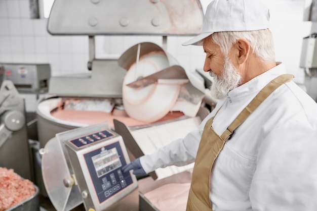 Trabajador parado cerca de equipos para moler carne.