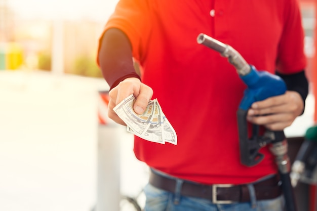 Foto el trabajador del personal de la estación de servicio devuelve el dinero por un precio más bajo del combustible, reducción de los costos del gas, reduce el precio de caída de la gasolina y paga el concepto de devolución de efectivo