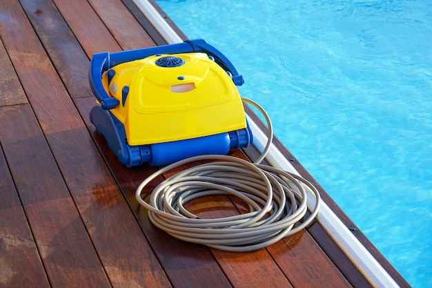 Trabajador del personal del hotel limpiando la piscina. Limpiafondos automáticos.