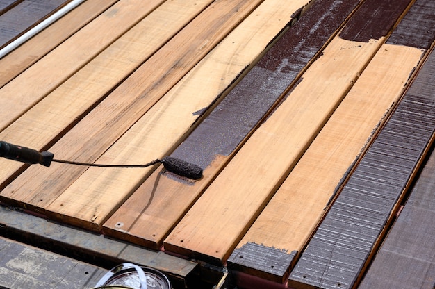 Trabajador pintando con rodillo de pintura sobre piso de madera