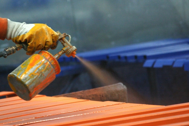 Trabajador de pintura de metal en fábrica.