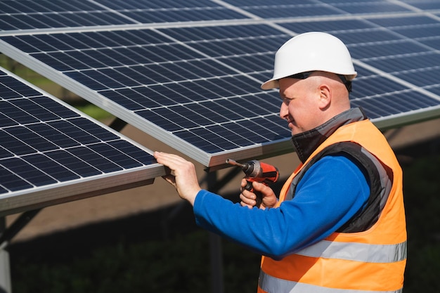 Trabajador de planta de energía solar con llave eléctrica en sus manos inspecciona paneles