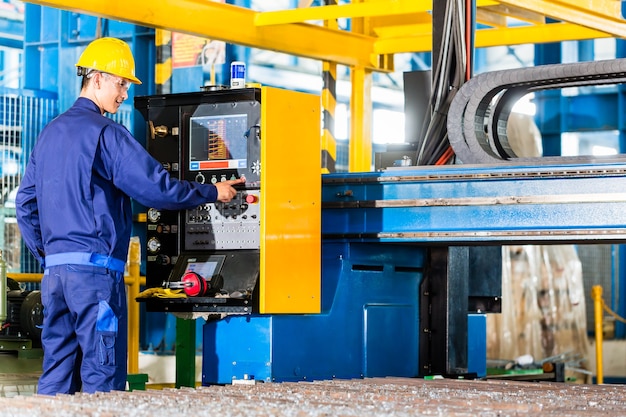 Foto trabajador en la planta de fabricación en el panel de control de la máquina cnc