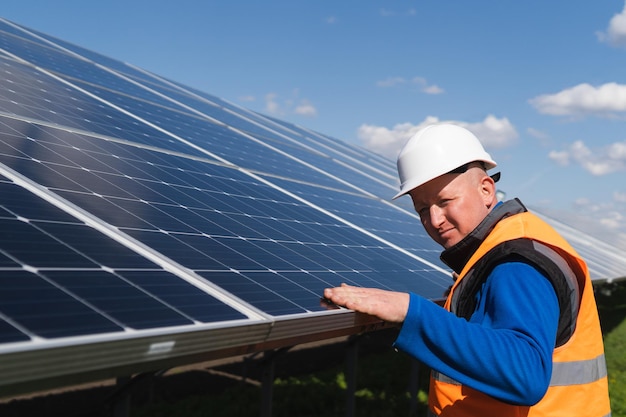Trabajador de planta solar inspeccionando paneles fotovoltaicos en busca de daños
