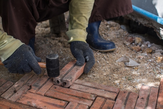 Foto trabajador poniendo camino de ladrillo rojo alrededor de la casa