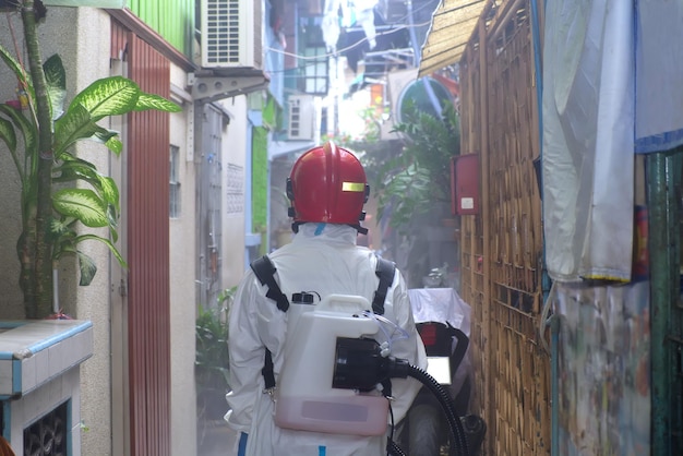 Trabajador en PPE trabajando en aldeas de solución química rociada para prevenir la epidemia de COVID19