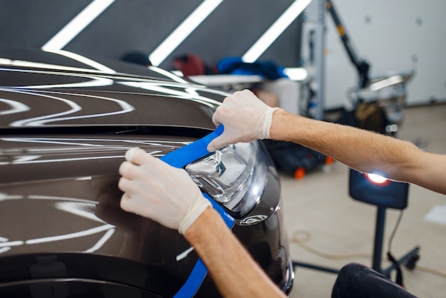 El trabajador prepara el coche para la aplicación de la película protectora