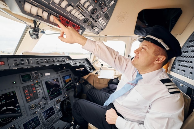 Trabajador profesional Piloto en ropa formal se sienta en la cabina y controla el avión