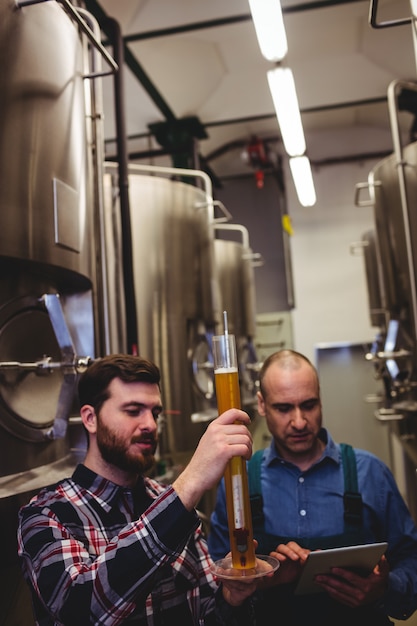 Trabajador y propietario inspeccionando cerveza en cervecería