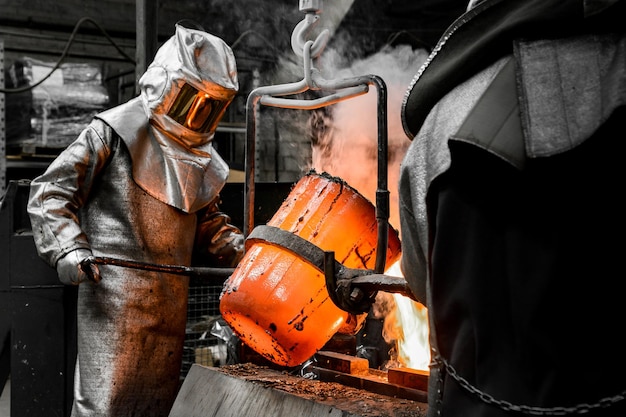 Un trabajador protegido por un traje de seguridad vierte el metal fundido en un molde