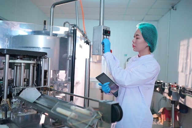 Foto trabajador que controla el trabajo de la máquina en la línea de producción en la industria de bebidas