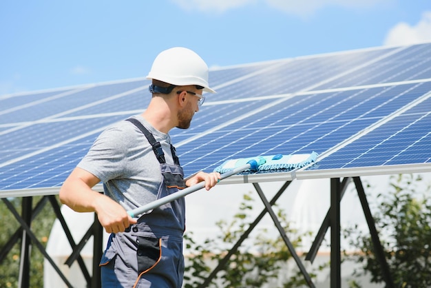 Trabajador que limpia los paneles solares después de la instalación al aire libre