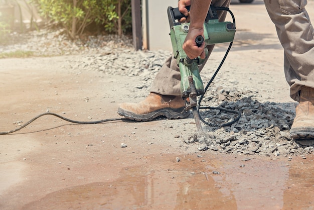 Trabajador que perfora la calzada concreta con el martillo neumático.