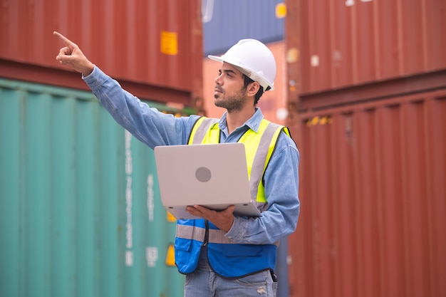 Trabajador que usa una computadora en un fondo de exportación de contenedores Ingeniero que usa una computadora en un fondo de importación de contenedores