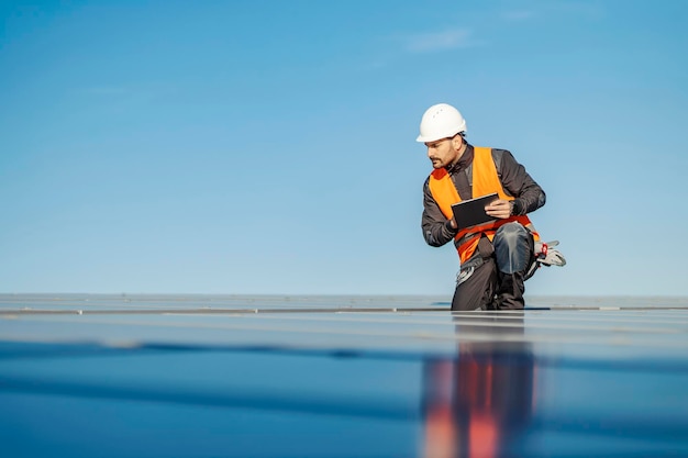 Un trabajador que usa una tableta para probar paneles solares en la azotea