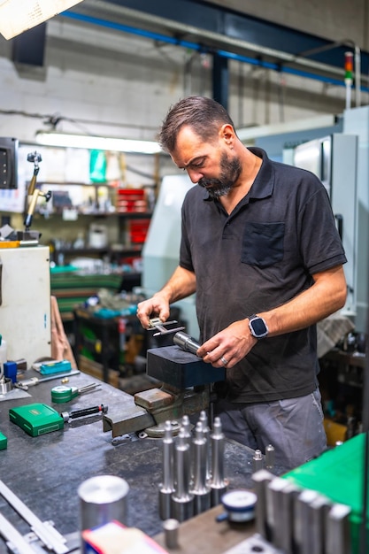 Trabajador que utiliza un micrómetro para medir piezas metálicas en una fábrica de CNC