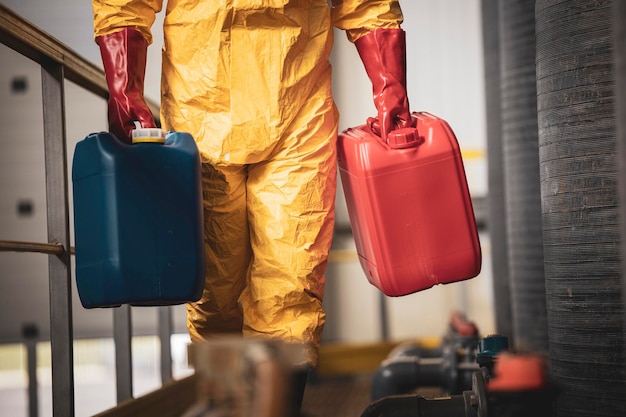 Trabajador químico irreconocible que lleva botes de plástico dentro de la fábrica