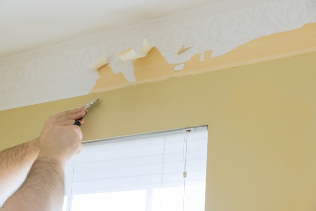 Trabajador de quitar un viejo papel tapiz de la pared