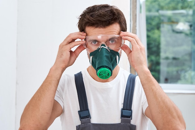 Foto trabajador de renovación con gafas protectoras y respirador retrato de trabajador de reparación en el hogar