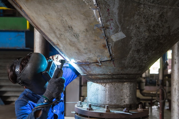 Trabajador de reparación de soldadura de tanque de fondo de silo de acero inoxidable con soldador tig