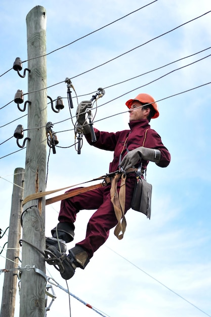 El trabajador reparador de liniero electricista instala la conexión a tierra en la línea eléctrica antes de repararla.