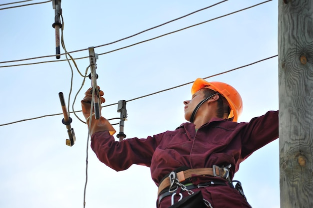 Foto el trabajador reparador de liniero electricista instala la conexión a tierra en la línea eléctrica antes de repararla.