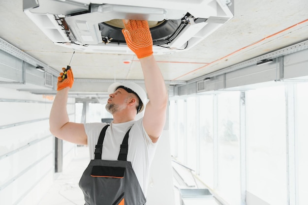 Trabajador reparando unidad de aire acondicionado de techo