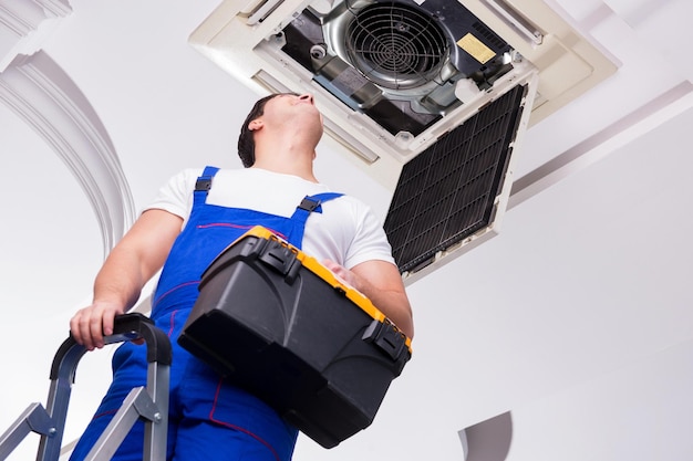 Foto trabajador reparando unidad de aire acondicionado de techo