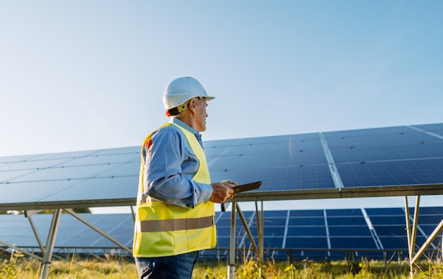 Trabajador revisando paneles solares con tableta en granja solar Eco energy