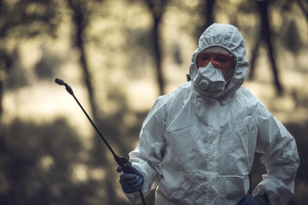 Un trabajador rocia pesticidas en los árboles al aire libre Control de plagas de árboles