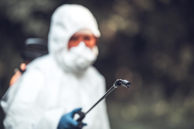 Un trabajador rocia pesticidas en los árboles al aire libre Control de plagas de árboles