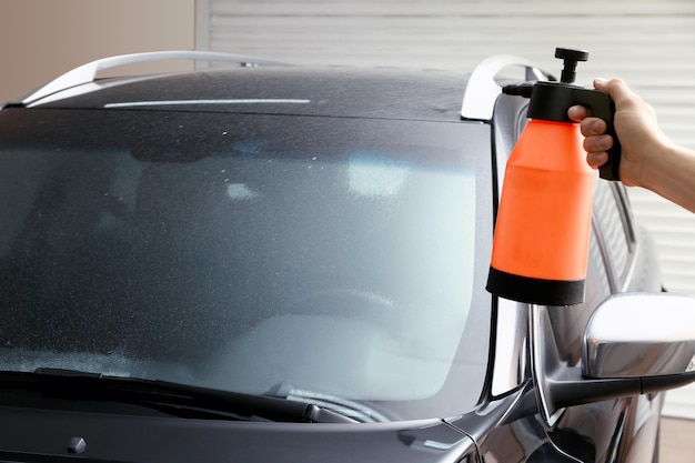 Trabajador rociando agua en la ventana del automóvil antes de teñir