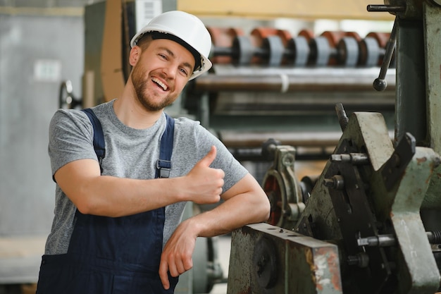 Trabajador en ropa protectora en fábrica usando máquina