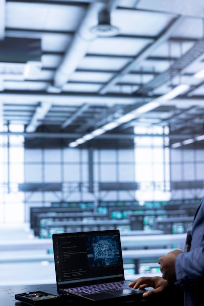 Trabajador de la sala de servidores ejecutando código en la computadora portátil para actualizar los sistemas de inteligencia artificial